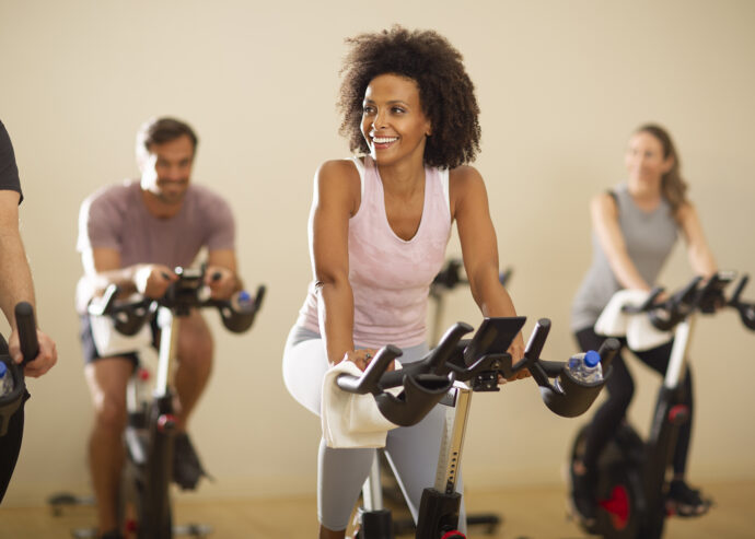 Group indoor cycling class with smiling woman leading the session