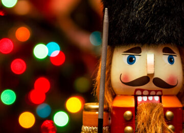 Classic nutcracker in front of colorful blurred Christmas lights