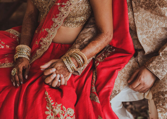 Closeup of Indian couple holding hands showcasing Mehndi.