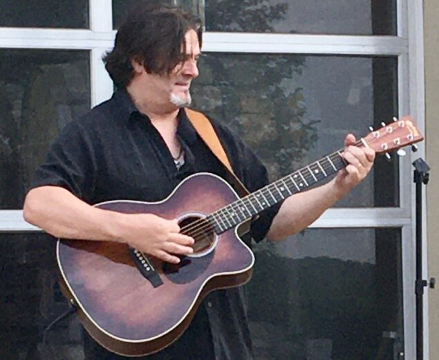 Gary Smallwood musician in black shirt performing live with an acoustic guitar