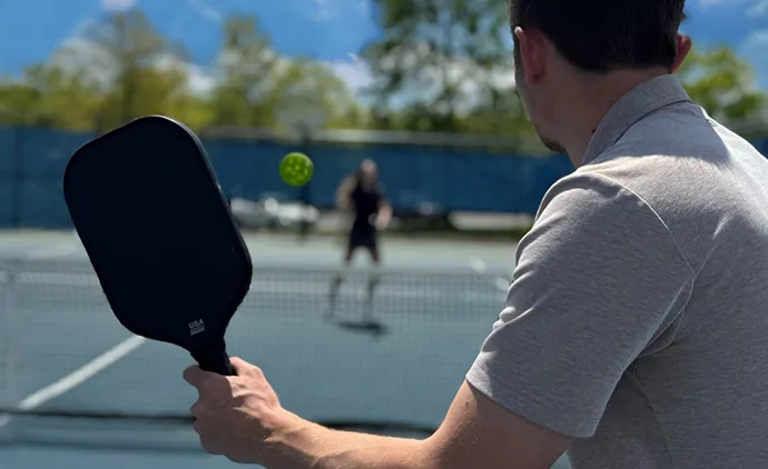 Two people enjoying a game of pickleball on a bright, sunny day.